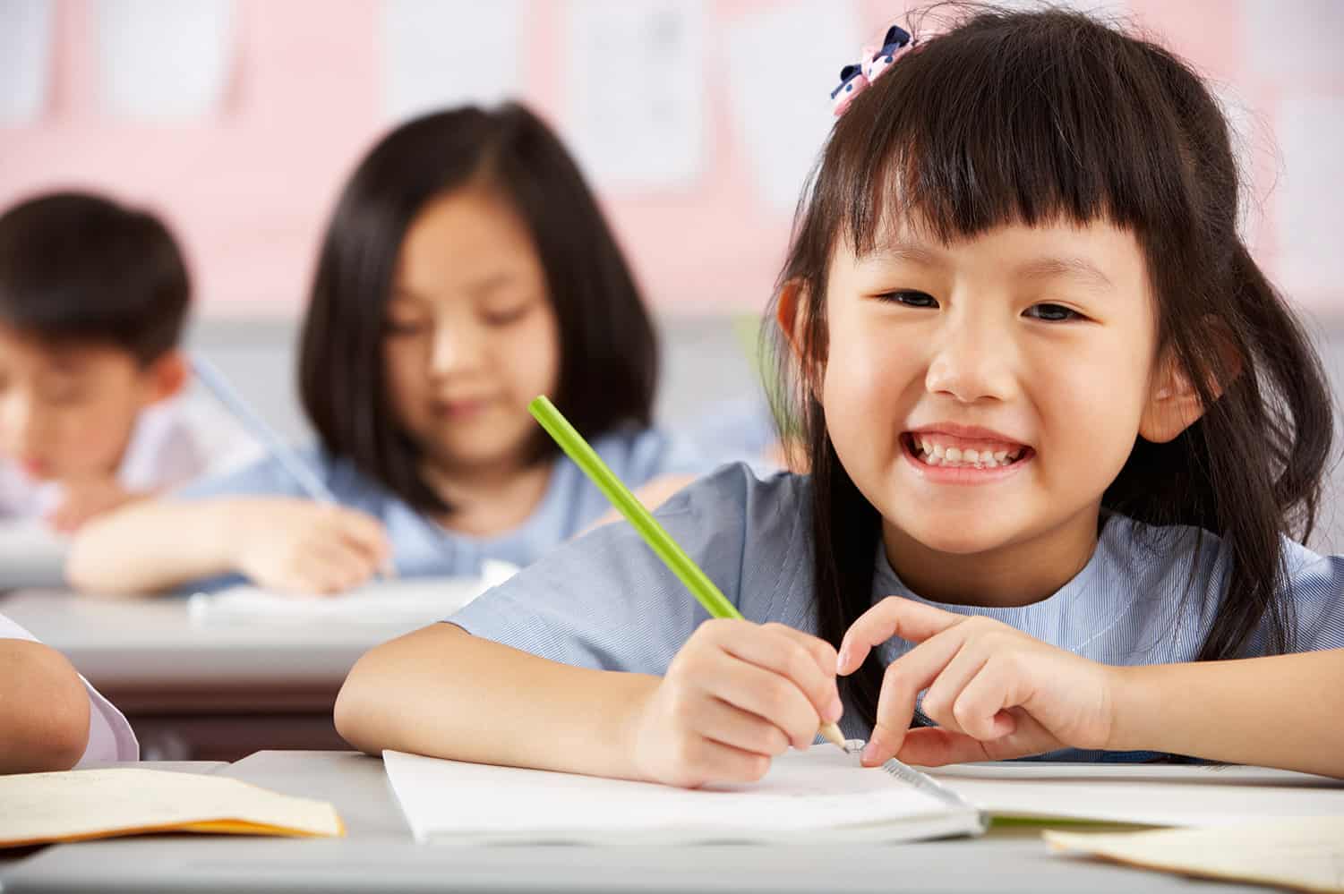 Girl studying and smiling for the camera in a good tuition centre